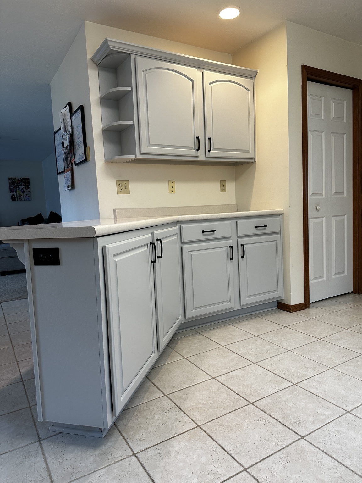 Light gray raised-panel cabinetry with black handles and curved open corner shelves